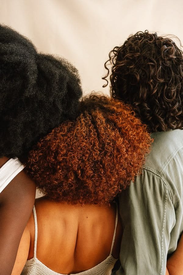 Friends with different natural curl patterns standing together